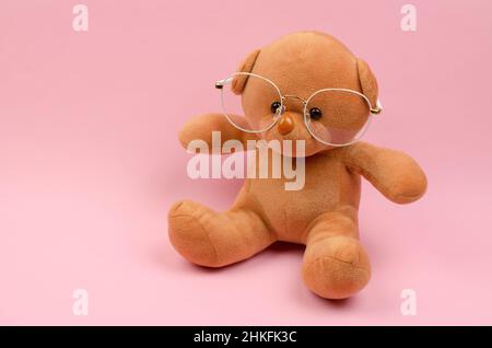 Orsacchiotto in occhiali per la visione su sfondo rosa Foto Stock