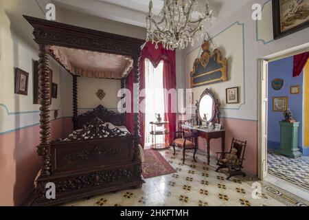 Malta, Valletta, camera da letto della Casa Rocca piccola, un palazzo del 16th secolo che ospita un museo privato e un bed and breakfast, decorato con un letto a baldacchino in legno, un lampadario di cristallo e un tavolo da pranzo wc con specchio Foto Stock