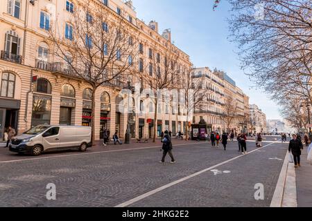 Marsiglia, Francia - 28 gennaio 2022: Edifici tipici francesi e persone che camminano a la Canebiere, una delle strade più trafficate della città di Marsiglia, Franc Foto Stock