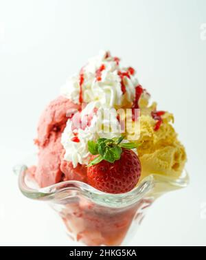 Tazza con tre palline di banana, panna e gelato alla fragola Foto Stock