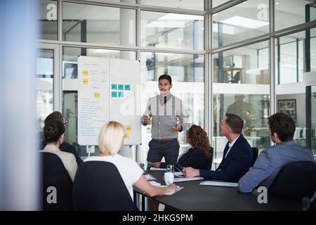 E questo è tutto in breve. Shot di un giovane uomo d'affari che spiega le cose relative al lavoro durante una presentazione ai colleghi di lavoro in una sala riunioni Foto Stock