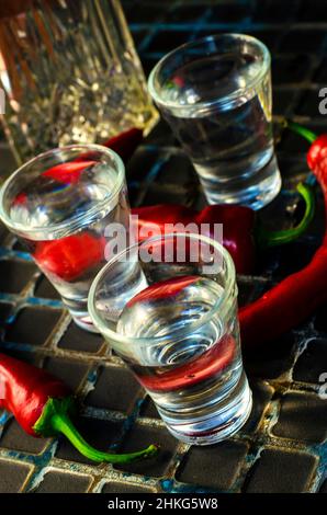 bicchiere di vodka con peperoni caldi su sfondo scuro Foto Stock