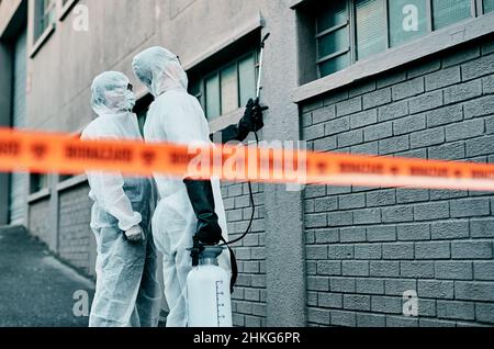 Tali finestre devono essere fissate. Shot di due operatori sanitari che indossano tute di nocciolo che lavorano insieme per controllare un focolaio. Foto Stock