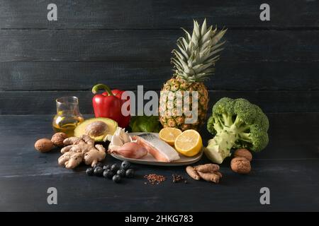 Cibo per la salute, verdure, pesce, frutta, noci e spezie per una dieta anti-infiammatoria e antiossidante, sfondo rustico scuro in legno con copia spac Foto Stock