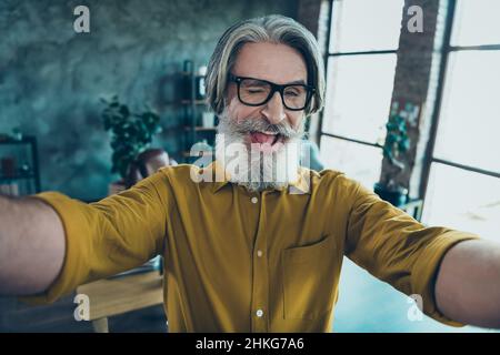 Autoritratto di attraente allegro capo uomo alla moda grigio-capelli wiching divertirsi sul posto di lavoro workstation in ambienti chiusi Foto Stock