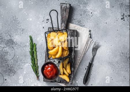 Immergere i spicchi di patate fritte con rosmarino e salsa di pomodoro in un cestino. Sfondo grigio. Vista dall'alto Foto Stock