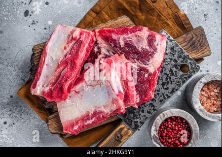 Manzo costolette di vitello kalbi, carne cruda su tavola macellaio in legno. Sfondo grigio. Vista dall'alto Foto Stock