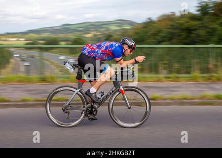 Ciclismo maschile in bicicletta da strada Giant sport su percorso di campagna attraversando il ponte autostradale in campagna Lancashire, Regno Unito Foto Stock