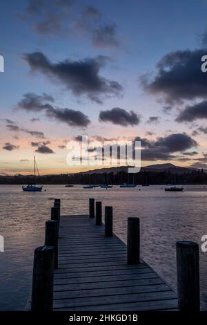 tramonto sul lago windermere con molo e barche all'ancora Foto Stock