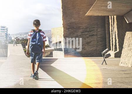 Vista posteriore di un giovane ragazzo con zaino, passeggiando in un contesto urbano. Studente alla moda a piedi al di fuori del college dopo un giorno di scuola. La gioventù, nuovo gene Foto Stock