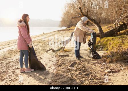 Due volontari puliscono i rifiuti da un fiume Foto Stock