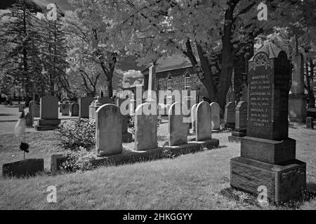 Un cimitero molto vecchio in un cortile della chiesa di riforma inglese del 1776. Questa foto infrarossa, astratta, in bianco e nero è spaventosa e un buon look per Halloween. Foto Stock