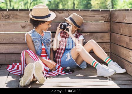 Bambini amici che giocano insieme all'aperto. Belle bambine che scattano foto con le fotocamere. Divertimento estivo, concetto di vacanze Foto Stock