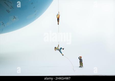 gli arrampicatori si tirano su una corda fino a un globo Foto Stock