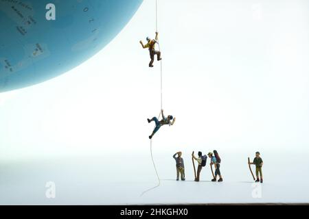 un gruppo di alpinisti guarda gli alpinisti che si tirano su un globo con una corda. Foto Stock