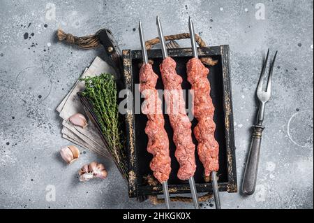 Shish kebab di carne di manzo e di agnello trito crudo, kebab adana turco. Sfondo grigio. Vista dall'alto Foto Stock
