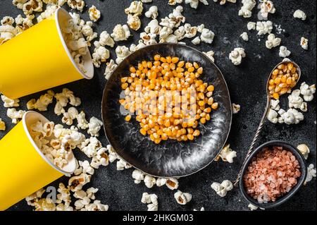 Popcorn al burro salato con nocciolo di mais e sale. Sfondo nero. Vista dall'alto Foto Stock