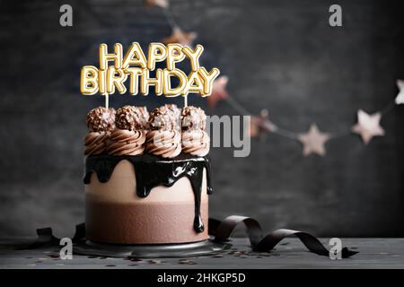 Torta di compleanno al cioccolato con glassa di ganache al cioccolato e banner di buon compleanno Foto Stock