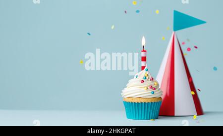 Cupcake di compleanno con una candela di compleanno e cappello da festa a strisce rosso e bianco Foto Stock