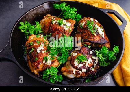 Cosce di pollo all'olio d'oliva arrosto stile mediterraneo: Cosce di pollo macinate di spezie tostate in una padella in ghisa Foto Stock