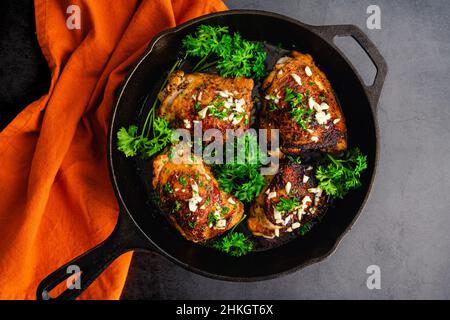 Cosce di pollo all'olio d'oliva arrosto stile mediterraneo: Cosce di pollo macinate di spezie tostate in una padella in ghisa Foto Stock