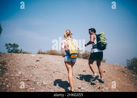Viaggiando in coppia camminando su strada vuota con zaini Foto Stock
