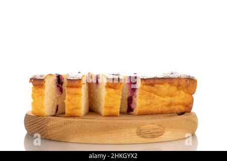 Diverse fette di caseruola casereccia di formaggio con ciliegie su un vassoio di legno, macro, isolato su uno sfondo bianco. Foto Stock