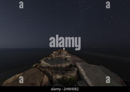 Mare con cielo stellato di notte visto dalla scogliera Foto Stock