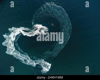 Vista aerea su una traccia a forma di cuore sul mare turchese da una moto d'acqua. San Valentino amore simbolo di forma del cuore, amore, sentimenti. Gli spruzzi d'acqua amano il cuore Foto Stock