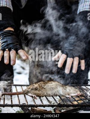 Le mani commoventi di un uomo senza tetto sulla griglia di un ratto, vista ravvicinata. Foto Stock