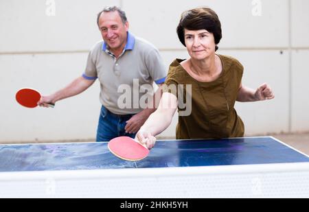uomo maturo e donna che gioca a ping pong Foto Stock