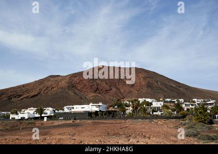 Ville e sviluppo turistico sotto il rosso montana Roja vulcano estinto vicino playa blanca Lanzarote Isole Canarie Spagna Foto Stock