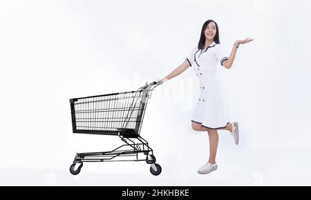 donna asiatica felice con carrello di shopping su sfondo bianco isolato per la pubblicità in business vendere e acquistare concetto di shopping. Foto Stock