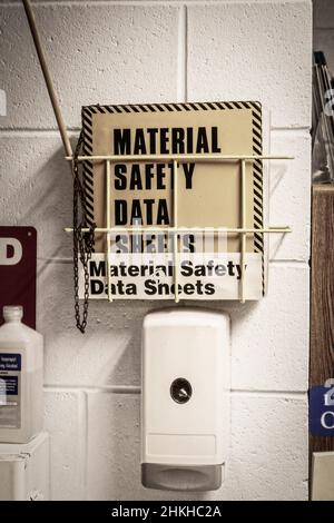 Igienizzatore manuale e schede di sicurezza msds montati su una parete in blocchi di calcestruzzo sul luogo di lavoro Foto Stock