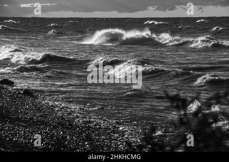 Immagini in bianco e nero di onde che si infrangono sulla spiaggia di Fresh Water Lake Ontario Canada in autunno giorno orizzonte e le nuvole in background Foto Stock