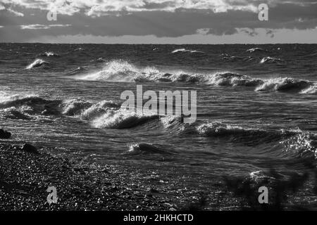 Immagini in bianco e nero di onde che si infrangono sulla spiaggia di Fresh Water Lake Ontario Canada in autunno giorno orizzonte e le nuvole in background Foto Stock