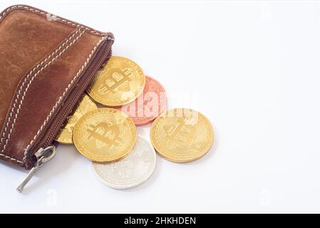 Alcune monete metalliche bitcoin sporgono da una borsa isolata su sfondo bianco. Oro Bitcoin, argento, bronzo, rame. Foto Stock