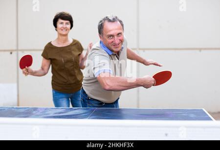 uomo maturo e donna che gioca a ping pong Foto Stock