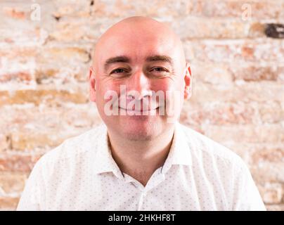 ritratto di calvo adulto maturo uomo con emozioni contro muro di mattoni Foto Stock