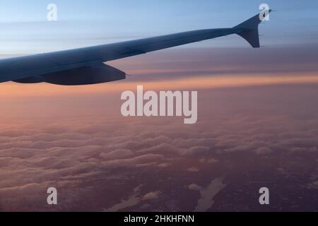 Vista dei passeggeri dell'ala dell'aereo sulle nuvole rosa del tramonto, Lapponia, Finlandia Foto Stock