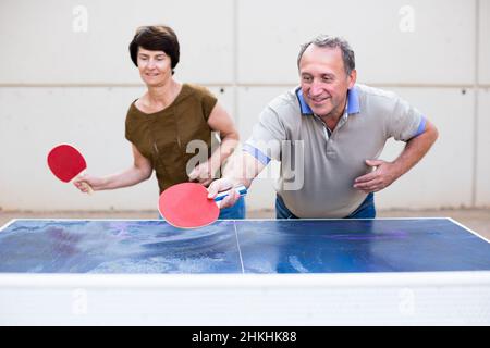 Felice matura spousesn giocare a ping pong Foto Stock