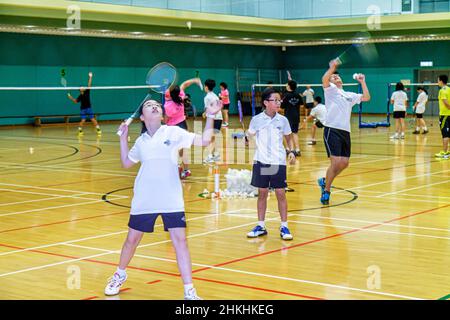 Hong Kong Chinese Island, Hong Kong Park Sports Center, centro, campi da badminton, palestra coperta, ragazzi asiatici ragazze studentesse che praticano servizio Foto Stock