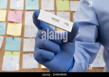 Impiegato d'ufficio che mostra test rapido antigene PCR positivo, timeline occupato e sic Foto Stock