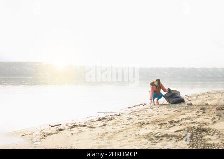 Giovane donna che raccoglie la spazzatura da una spiaggia Foto Stock