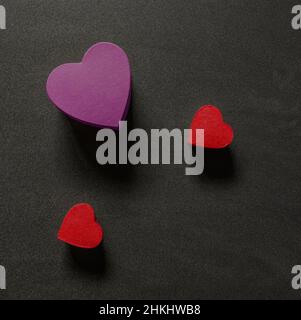 Un cuore viola e due rosso si forma su uno sfondo scuro dall'alto Foto Stock