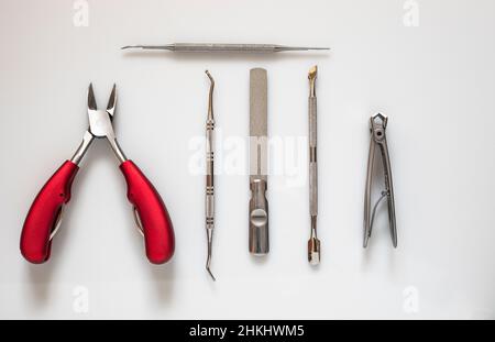 utensili di podiatria su uno sfondo bianco luminoso tagliatori con manici rossi raccolta di articoli si stendere piatto da sopra Foto Stock