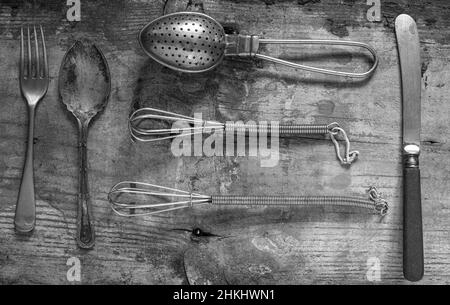 primo piano su antichi utensili da cucina in vecchio stile su uno sfondo rustico dall'alto fotografato in bianco e nero Foto Stock