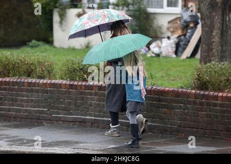 Londra, Regno Unito. 04th Feb 2022. Una donna con il suo bambino cammina lungo una strada mentre tiene gli ombrelloni durante la pioggia. (Foto di Steve Taylor/SOPA Images/Sipa USA) Credit: Sipa USA/Alamy Live News Foto Stock