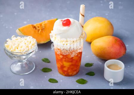 Mango e melone bevanda ghiacciata con gelato decorato su un tavolo grigio Foto Stock