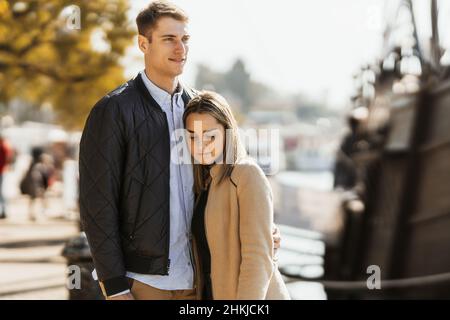 Una giovane ragazza bionda appoggia la testa sul petto del ragazzo mentre guarda verso il basso il terreno. Foto Stock